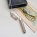 Vintage silver needle case on a white surface with an old book and vintage-style illustration.