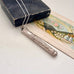 Vintage silver needle case on a white surface with an old book and vintage-style illustration.