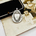 Vintage 1932 Fattorini sterling silver 1932 watch fob pendant with ornate detailing, displayed on top of an antique sepia-toned photograph and a black jewelry box.