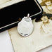Back of vintage 1932 Fattorini sterling silver 1932 watch fob pendant with ornate detailing, displayed on top of an antique sepia-toned photograph and a black jewelry box.