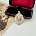 Silver medallion with a rose gold center in an open velvet box on a white surface with an old photograph.
