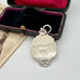 Silver pendant with 'H. Collins 1951' engraved, displayed in an open velvet box.