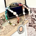 Vonk Jewellery 1933 watch fob multi pearl, crystal and gemstone necklace on a vintage jewellery box and vintage postcards 