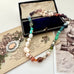 Vonk Jewellery 1933 watch fob multi pearl, crystal and gemstone necklace on a vintage jewellery box and vintage postcards 