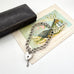 Vintage 1974 Silver chain bracelet with a heart-shaped padlock on an old postcard with decorative elements.