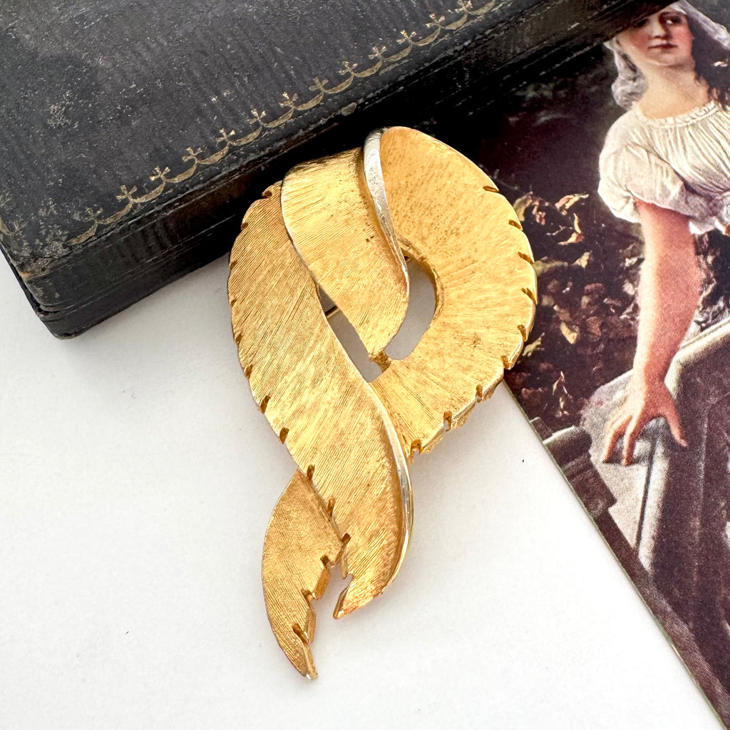 Vintage 1960's signed Coro  brushed gold tone brooch on a vintage postcard