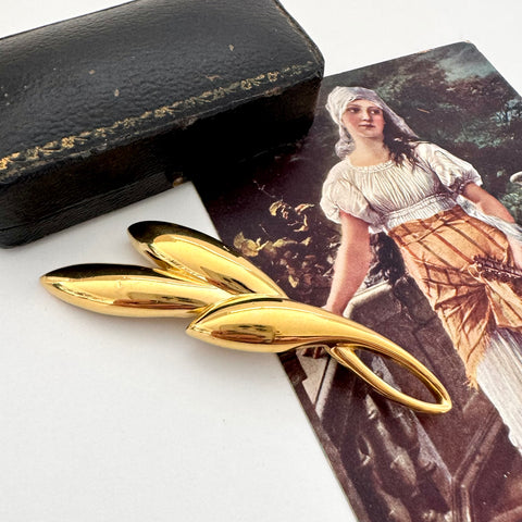 Vintage gold trifari brooch on a vintage postcard and with a vintage jewellery box in the background