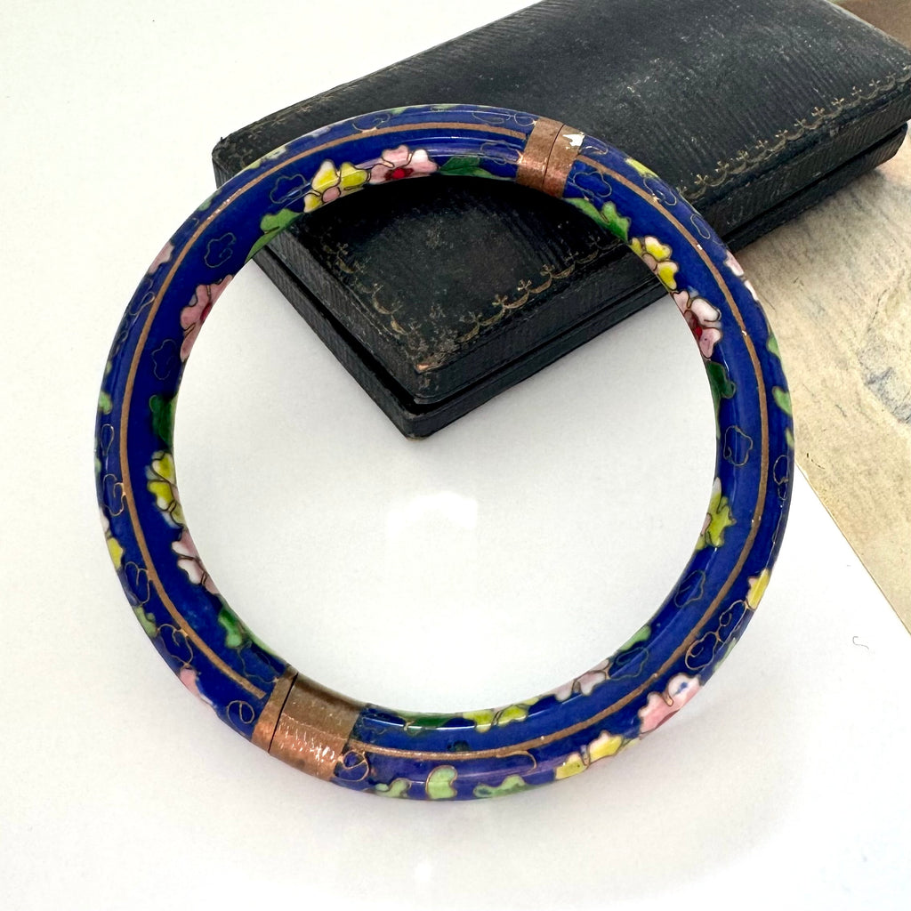 Decorative blue cloisonne bangle with floral patterns on a white surface