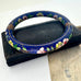 Decorative blue  cloisonne bangle with floral patterns on a white background