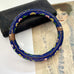 Decorative blue cloisonne bangle with floral patterns on a textured surface