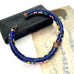 Blue cloisonne floral-patterned bracelet on a textured surface with a black box.