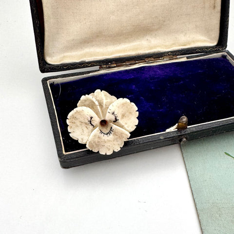 Vintage flower pansy brooch in an open jewelry box on a white background