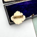 Vintage brooch with a white floral design in an open jewelry box on a white background