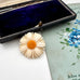 Vintage Danish hand carved daisy shaped brooch on a floral-patterned card with an open jewelry box.