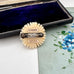 Decorative vintage daisy brooch with 'Elfenben' and 'Danish Handcarved' labels on a floral background