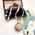 Multicolored beaded necklace with a vintage gilt locket  on a white surface with an open jewelry box and vintage card.