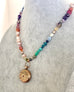 Necklace with multicolored beads and a gold pendant on a mannequin.
