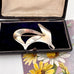 Silver Norwegian Ivar T Holth brooch on a floral card with an open jewelry box in the background