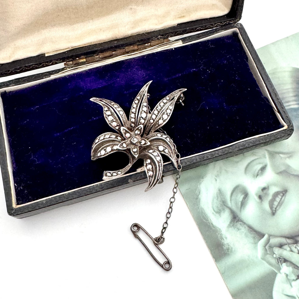 Silver marcasite brooch with leaf design on a blue velvet background