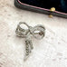 Silver and marcastie bow-shaped brooch on a textured surface