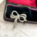 Silver  and marcasite bow-shaped brooch in a jewelry box on a textured surface