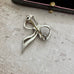 Back of silver and marcasite bow-shaped brooch on a textured surface