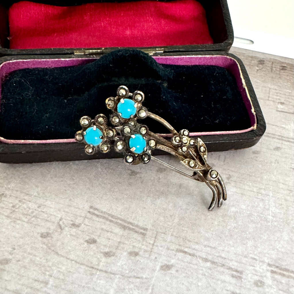Vintage brooch with turquoise stones in a black case on a textured surface