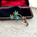 Vintage brooch with turquoise stones in a black case on a textured surface