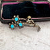 Vintage brooch with turquoise stones and marcasite silver accents in a box on a textured surface