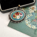 Vintage micro mosaic brooch on an old postcard