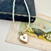 Pearl and larimar necklace with a vintage  heart-shaped mother of pearl and gold locket on an old box and fan illustration