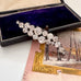 Vintage 1960's rhinestone brooch in a black box with a scenic postcard in the background