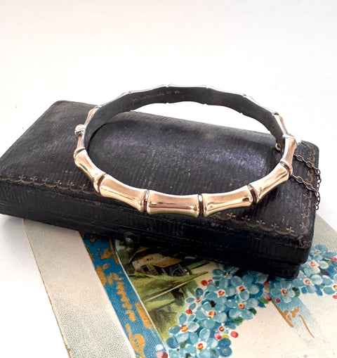 Vintage rolled gold on sterling silver bamboo-style bracelet on a black leather surface with a floral card underneath.