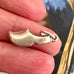 Silver Dutch shoe charm held between fingers with a blurred background
