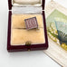 A vintage emergancy money 10 shilling silver pendant , displayed inside an open antique presentation box next to an old illustrated card.
