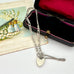 Silver chain necklace with heart-shaped tag on a white surface next to an open jewelry box.