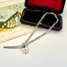 Silver chain necklace with a heart-shaped lock pendant on a white surface.