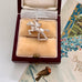 Vintage silver equestrian charm in a jewelry box on an old letter with decorative elements.