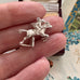 Vintage silver equestrian charm in a woman's fingers.