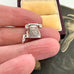 Silver telephone charm held between fingers with vintage photo in the background
